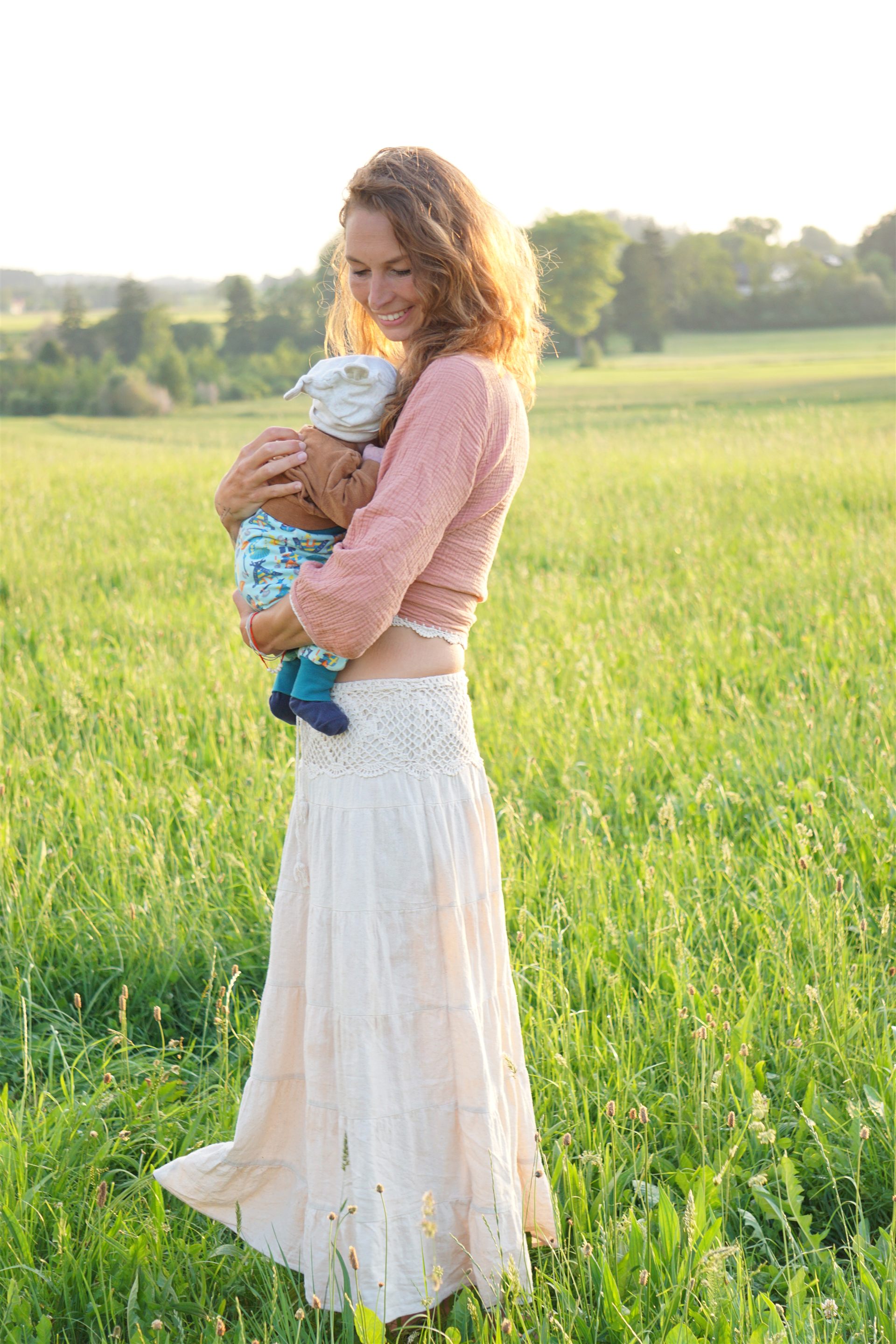 Jacqueline Geggier mit einem Baby auf einer Wiese